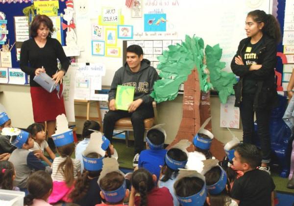 A student reading to a group of young children.